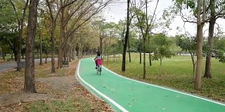 女人骑着自行车，用智能手机带着她的相机