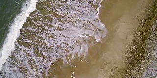 一个少女走在蒙托克角的海岸上。航拍镜头，正上方的景色。