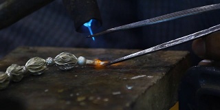 男人手工制作的银项链用煤气燃烧来粘合