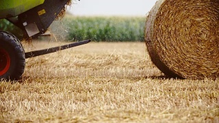 拖拉机释放一捆干草，稻草。农业的背景。视频素材模板下载