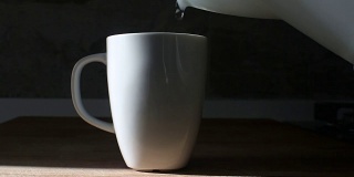 从水壶中倒入滚烫的开水到白咖啡或茶杯中