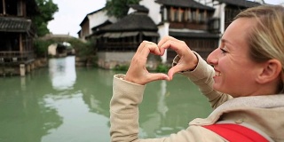 中国农村的一名年轻女子制作心形手指架