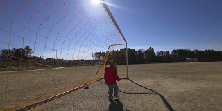 一个小男孩在足球场上独自玩耍