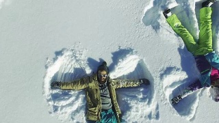 鸟瞰图两个人正在做一个雪天使，视频素材模板下载