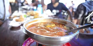 俯视图热辣的泰国咖喱，酸汤蔬菜和泰国香草，泰国著名风格的火锅在餐厅。