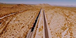 无人机在荒芜的美国沙漠中跟踪一辆大型集装箱机车。