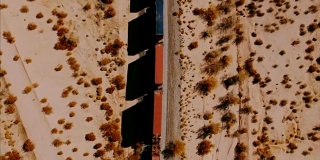 一架美丽的无人机在沙漠中向下俯瞰一列经过的集装箱火车。