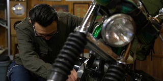 一个男人在他的车库里打磨和维护他的定制摩托车