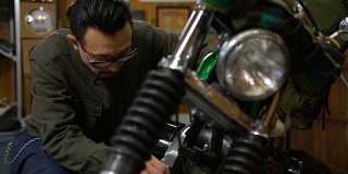 一个男人在他的车库里打磨和维护他的定制摩托车