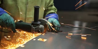 工人用角磨床在金属片上进行切割。