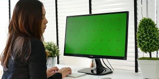女士使用绿色屏幕的电脑显示器