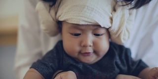 CU:亚洲婴儿和他的母亲在家里阅读