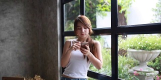 年轻女子在大窗户附近使用手机