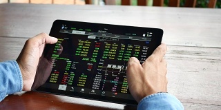 Over shoulder view的商人使用平板电脑分析股票市场