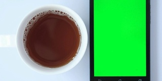 绿色屏幕的手机咖啡在白色背景。
