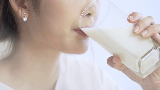 美丽的年轻女子喝牛奶是健康的微笑视频素材模板下载