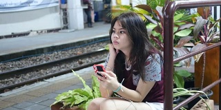 女孩在等火车的时候用手机