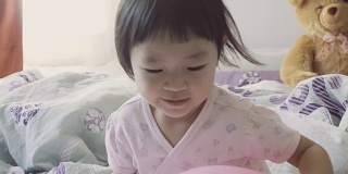 亚洲小女孩在床上玩粉红色的气球