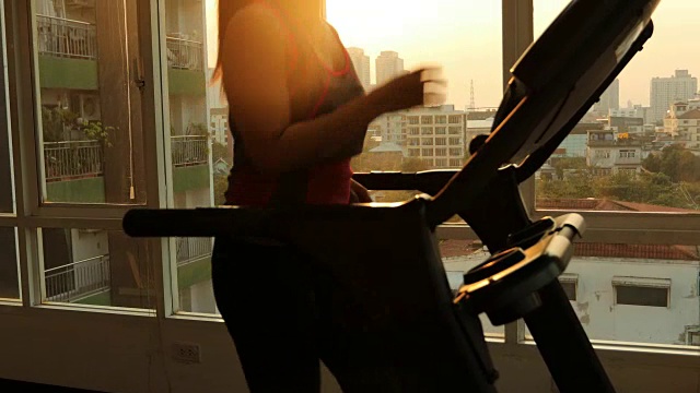 年轻的亚洲女子在跑步机上锻炼