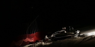 使滑雪场平整的机器在夜间工作。