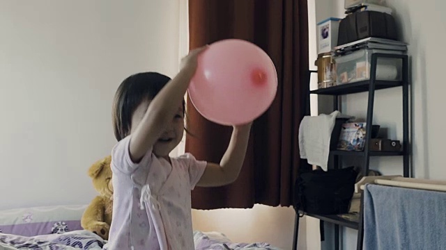 Asian Young Girl Playing Pink Balloon On Bed