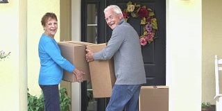 老夫妇把纸板箱从房子搬到车里