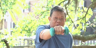 年长的亚洲男子在公园里练哑铃