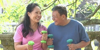 年老的亚洲夫妇聊天，在公园里锻炼
