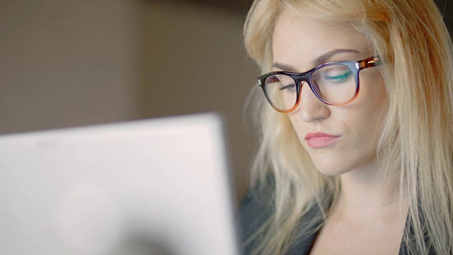 职场女性在办公室使用笔记本电脑时戴眼镜