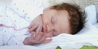 两周大的婴儿正在睡觉，捂着脸，仔细看视频，选择性聚焦