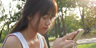 女人用智能手机和她的朋友在花园里聊天