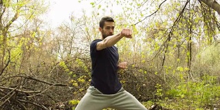 一个年轻人在春天的森林里练习空手道。