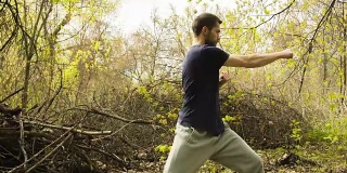 一个年轻人在春天的森林里练习空手道。
