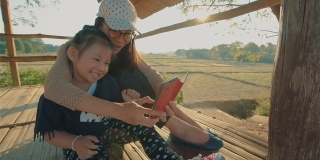 亚洲年轻母亲和女儿的孩子在户外用智能手机自拍