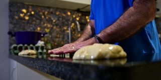 一个面包师在厨房台面上揉面团的慢动作镜头