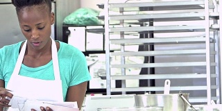 非裔美国妇女在面包店的厨房里付账单