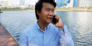 一个在户外玩手机的亚洲男人