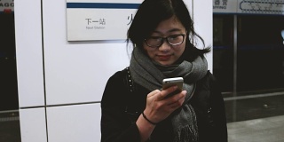 亚洲女孩在地铁站使用手机/北京，中国