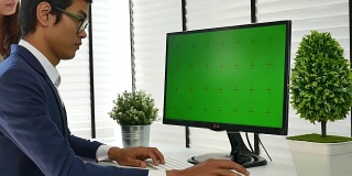 Two people using at the computer with green screen