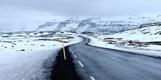 平移拍摄:道路延伸冰岛冬季景观雪山