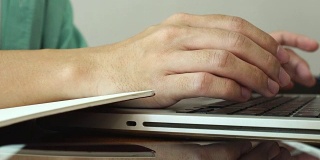 在家工作，用笔记本电脑写博客。咖啡店里男性的手在敲击键盘。