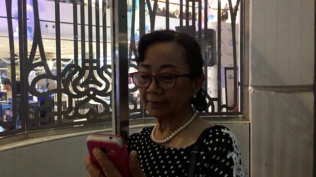 一位年长女性在电梯里使用智能手机