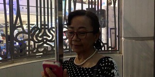 一位年长女性在电梯里使用智能手机
