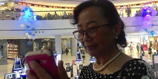 一位年长女性在电梯里使用智能手机