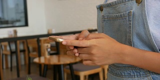 一个女人的手在咖啡店用智能手机