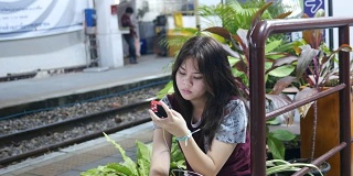 女孩在等火车的时候用手机