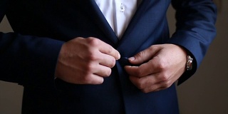 新郎在婚礼前扣上他的蓝色夹克