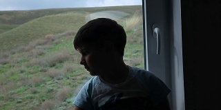 那个男孩坐在窗台上望着窗外