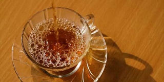 在泰国清晨的阳光下，将热茶倒入绿色的玻璃茶杯中