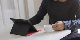 亚洲人使用平板电脑和喝咖啡